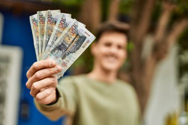 Genç İspanyol gülümseyen adam Peru tabanlı banknotları şehirde tutarken mutlu..
