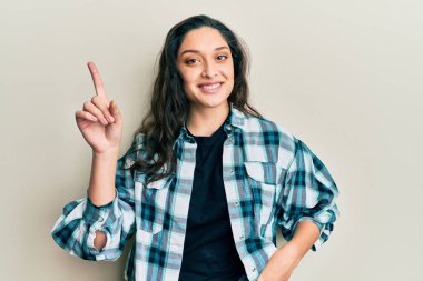 Güzel bir orta doğulu kadın gündelik kıyafetler giyip gülümsüyor bir fikir veya soruyla mutlu bir yüzle işaret ediyor. 