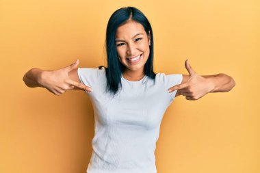 Güzel İspanyol kadın, günlük beyaz tişört giyiyor, kendine güveniyor, gülümsüyor, kendini gururlu ve mutlu bir şekilde gösteriyor.. 