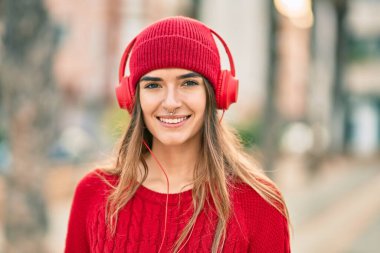 Şehirde kulaklık takan yün şapkalı genç İspanyol kadın..