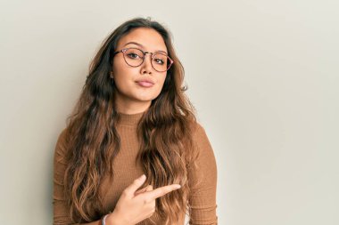 Gündelik kıyafetler giyen ve gözlük takan genç İspanyol kız el ile işaret ederek reklamını yapıyor, ciddi ve sakin bir yüz ifadesi var. 