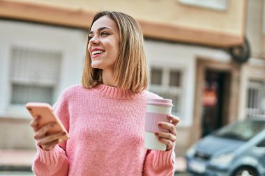 Beyaz kız akıllı telefon kullanıyor ve şehirde kahve içiyor..