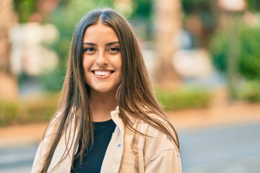 Genç İspanyol kız gülümseyerek şehirde mutlu mesut dikiliyor..