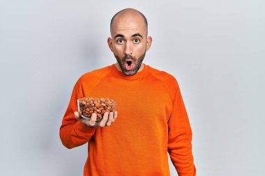 Fıstık tutan genç kel adam korkmuş ve ağzı açık hayret içinde şaşkınlık içinde, inançsız bir yüz. 