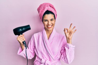 Duşta bornoz giyen, kurutma makinesi kullanan, parmaklarıyla imza atan, gülümseyen, dost canlısı hareketler yapan genç İspanyol kadın mükemmel bir sembol. 