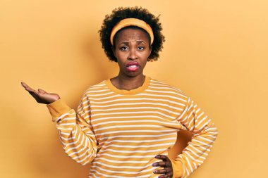 Genç Afro-Amerikalı kadın avuçlarını açmış elinde hiçbir şeyden habersiz ve kafası karışmış bir ifade tutuyordu. şüphe kavramı. 