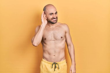 Mayo giyen genç ve kel bir adam kulağına fısıldayarak dedikodu ve dedikoduları dinliyor. Sağırlık kavramı. 