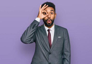 Genç Afro-Amerikan bir adam iş kıyafetleri giyiyor. Şaşırmış yüz ifadesiyle şaşırmış, parmaklarından bakan gözler. İnançsız ifade. 