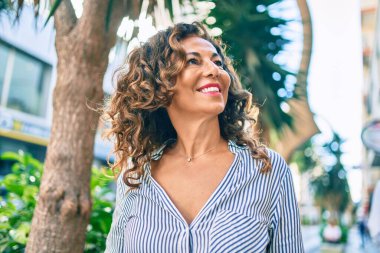 Orta yaşlı İspanyol kadın gülümseyerek şehirde mutlu mesut yürüyor..