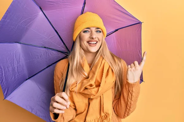 若いですCaucasian女性保持紫色の傘笑顔幸せなポインティングとともに手と指で側面 — ストック写真