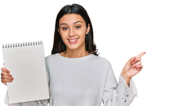 Menina Hispânica Jovem Segurando Notebook Sorrindo Feliz Apontando Com Mão — Fotografia de Stock