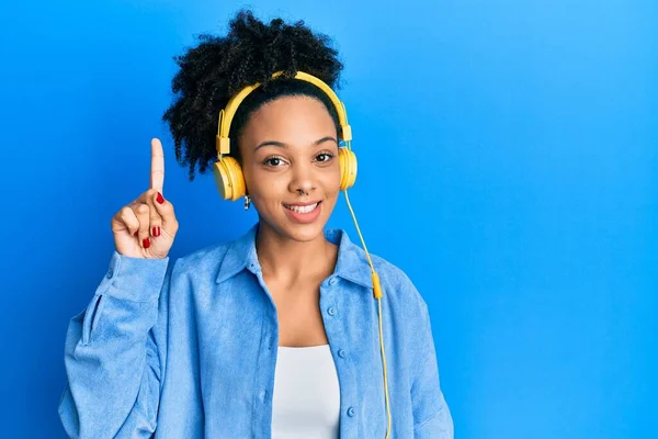 年轻的非洲裔美国女孩用耳机听音乐 指指点点 提出了一个成功的主意 又兴奋又快乐第一大 — 图库照片
