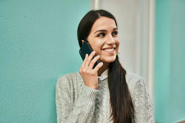 若いヒスパニック系の女性は 市内のスマートフォンで幸せな話を笑って — ストック写真