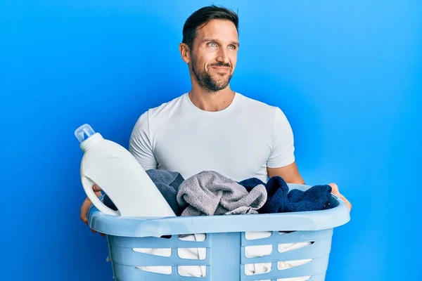 Young Handsome Man Holding Laundry Basket Detergent Bottle Smiling Looking — Φωτογραφία Αρχείου