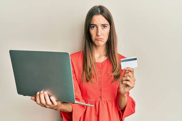 Joven Mujer Hermosa Sosteniendo Portátil Tarjeta Crédito Deprimido Preocuparse Por — Foto de Stock