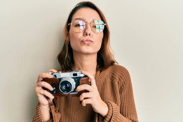 Mulher Caucasiana Jovem Segurando Câmera Vintage Olhando Para Câmera Soprando — Fotografia de Stock