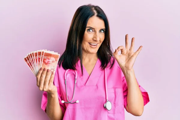 Middle Age Brunette Doctor Woman Holding Shekels Banknotes Doing Sign — 图库照片