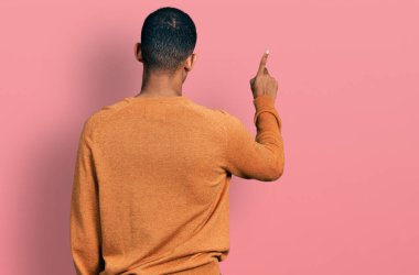 Genç, Afro-Amerikan bir adam, günlük kıyafetler giymiş, geriye doğru poz veriyor. 