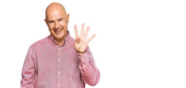 Orta yaşlı, kel bir adam dört numarayı gösterip gösterirken kendinden emin ve mutlu bir şekilde gülümsüyor.. 