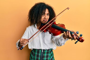 Afro saçlı güzel Afro-Amerikalı kadın klasik keman çalıyor şüpheci ve gergin, sorun yüzünden surat asıyor. negatif kişi. 