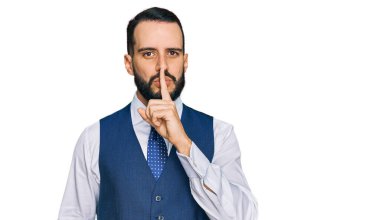 Sakallı, iş yeleği giyen genç bir adam parmakları dudaklarında sessiz olmak istiyor. sessizlik ve gizli konsept. 