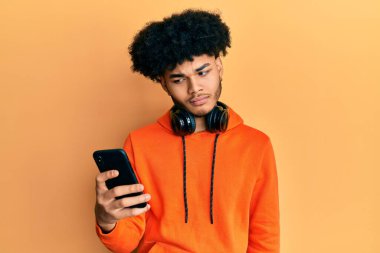 Afro saçlı, zeki telefon kullanan, kuşkucu ve sinirli, sorun yüzünden surat asan Afrikalı genç bir Amerikalı. negatif kişi. 