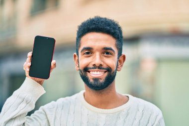 Genç Afrikalı Amerikalı adam gülümsüyor. Şehre akıllı telefon gösterdiği için mutlu..