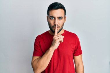 Gündelik kıyafetler giyen genç İspanyol adam parmakları dudaklarında sessiz olmak istiyor. sessizlik ve gizli konsept. 