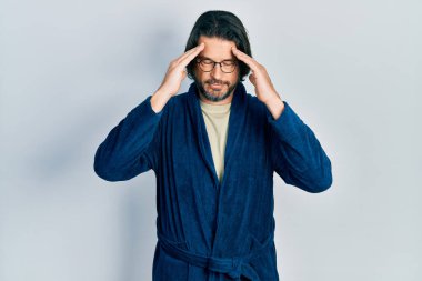 Kafkasyalı orta yaşlı bir adam bornoz giyiyor ve stres yüzünden kafasında baş ağrısı olan gözlüklü bir adam. migren ağrısı. 