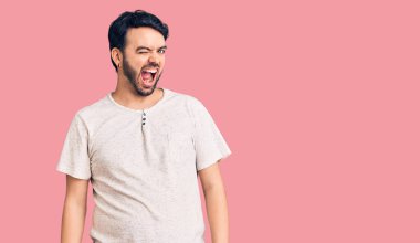 Gündelik kıyafetler giyen genç İspanyol adam kameraya seksi bir ifadeyle bakıyor, neşeli ve mutlu bir yüzle.. 