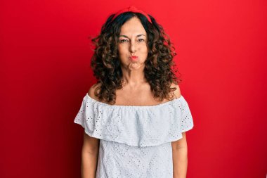 Orta yaşlı İspanyol kadın gündelik kıyafetler giyip komik yüzlü yanakları şişiriyor. Havayla şişmiş ağız, çılgın bir ifade.. 