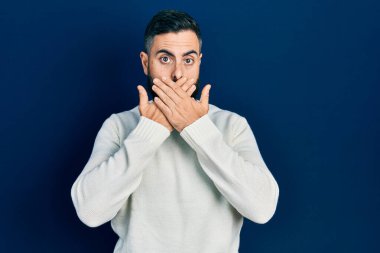 Gündelik kıyafetler giyen genç İspanyol adam yanlışlıkla elleri ile ağzını kapatırken şok oldu. gizli kavram. 