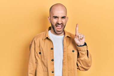 Gündelik giysiler giymiş genç kel adam başarılı bir fikirle işaret ediyor. Heyecanlı ve mutlu. Bir numara.. 