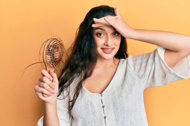 Güzel bir orta doğulu kadın elinde tarak tutuyor. Saçları dökülüyor, gergin ve hayal kırıklığına uğramış, şaşırmış ve kızgın bir yüzü var. 