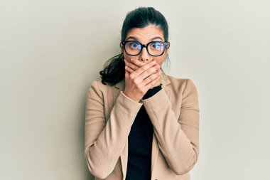 İş stili ve gözlük takan genç İspanyol kadın yanlışlıkla elleriyle ağzını kapatırken şok oldu. gizli kavram. 