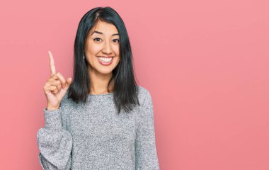 Gündelik giysiler giymiş güzel Asyalı genç bir kadın başarılı bir fikri işaret ediyor. Heyecanlı ve mutlu. Bir numara.. 