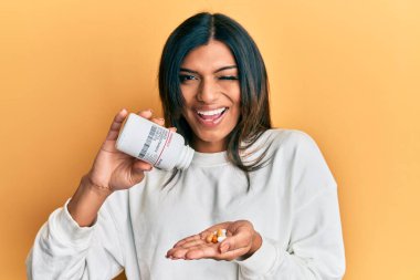 Genç Latin transseksüel kadın elinde haplarla kameraya bakıyor. Seksi bir ifadeyle, neşeli ve mutlu bir yüzle.. 