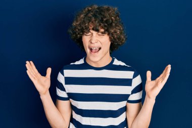 Yakışıklı, çizgili tişört giyen, çılgın ve başarıyı kutlayan, kollarını kaldırmış, gözlerini kapatmış heyecanlı çığlıklar atan genç adam. Kazanan konsept 