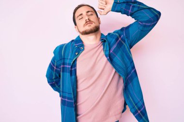 Genç, yakışıklı, rahat, rahat, rahat, rahat ve sabahları esneyen, gündelik kıyafetler giyen bir adam. 