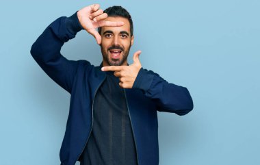 Gündelik kıyafetler giyen, gülümseyen, elleri ve parmakları gülen yüzlü, çerçeveli bir İspanyol. yaratıcılık ve fotoğrafçılık kavramı. 