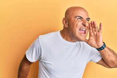 Olgun bir Orta Doğulu adam günlük beyaz tişört giyip el ele tutuşarak bağırıyor ve çığlık atıyordu. iletişim konsepti. 