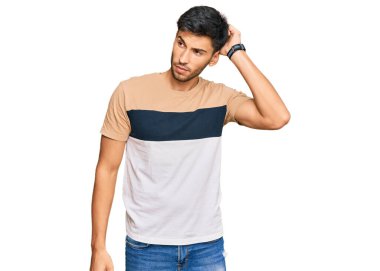 Gündelik giysiler giyen genç yakışıklı adam kafaları karıştırıyor ve soruyu merak ediyor. Şüpheyle kararsız, kafa kafaya düşünerek. Düşünceli kavram. 