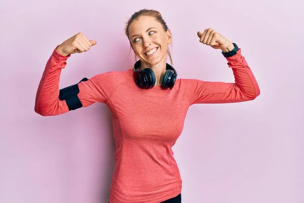 漂亮的高加索女人穿着运动服和臂章 露出胳膊肌肉 露出自豪的笑容 健身概念 — 图库照片