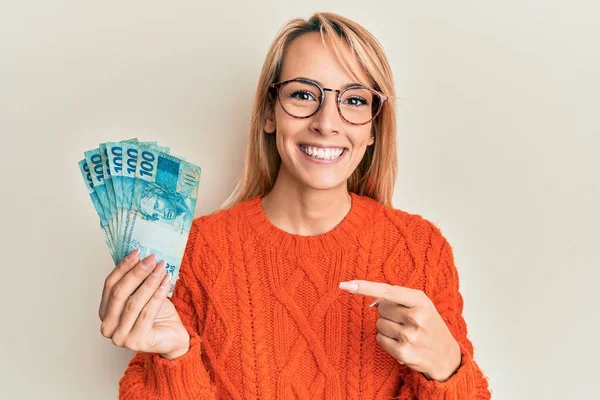Beautiful Blonde Woman Holding 100 Brazilian Real Banknotes Smiling Happy — Stock Photo, Image