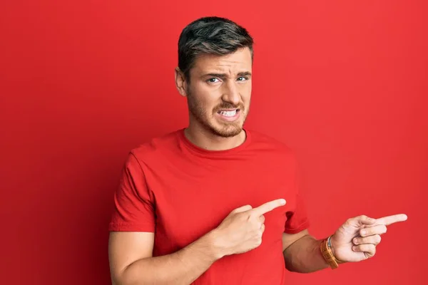 Knappe Blanke Man Draagt Casual Rood Tshirt Wijzen Opzij Bezorgd — Stockfoto