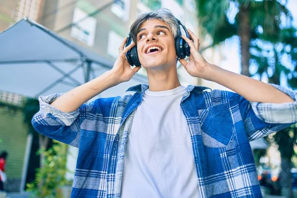 若いヒスパニック系の男は 市内を歩くヘッドフォンを使用して幸せな笑顔 — ストック写真