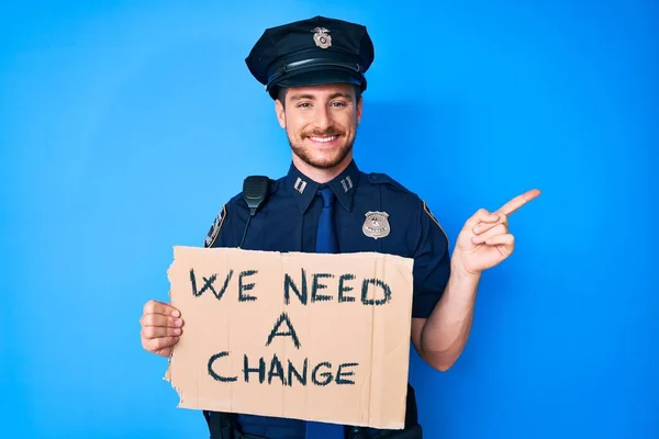 Young Caucasian Man Wearing Police Uniform Holding Need Change Banner — Zdjęcie stockowe