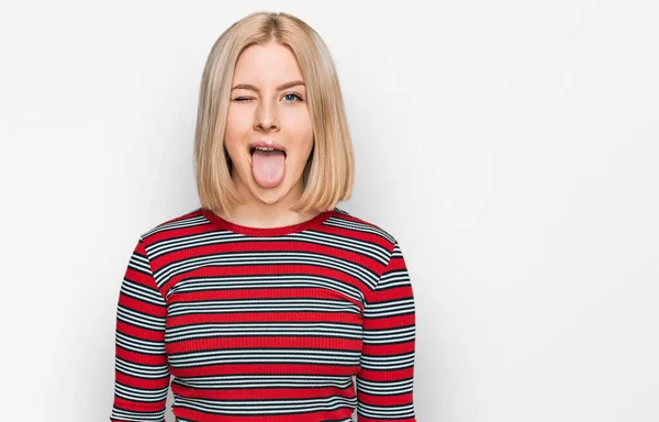 面白い表情で嬉しそうに舌を突き出しているカジュアルな服を着た若いブロンドの女性 感情の概念 — ストック写真