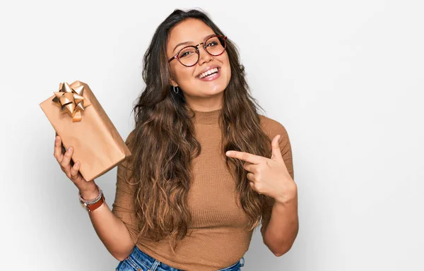 Jong Hispanic Meisje Houden Geschenk Glimlachen Gelukkig Wijzend Met Hand — Stockfoto