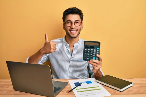 Jovem Empresário Trabalhando Com Calculadora Mostrando Polegares Para Cima Feliz — Fotografia de Stock